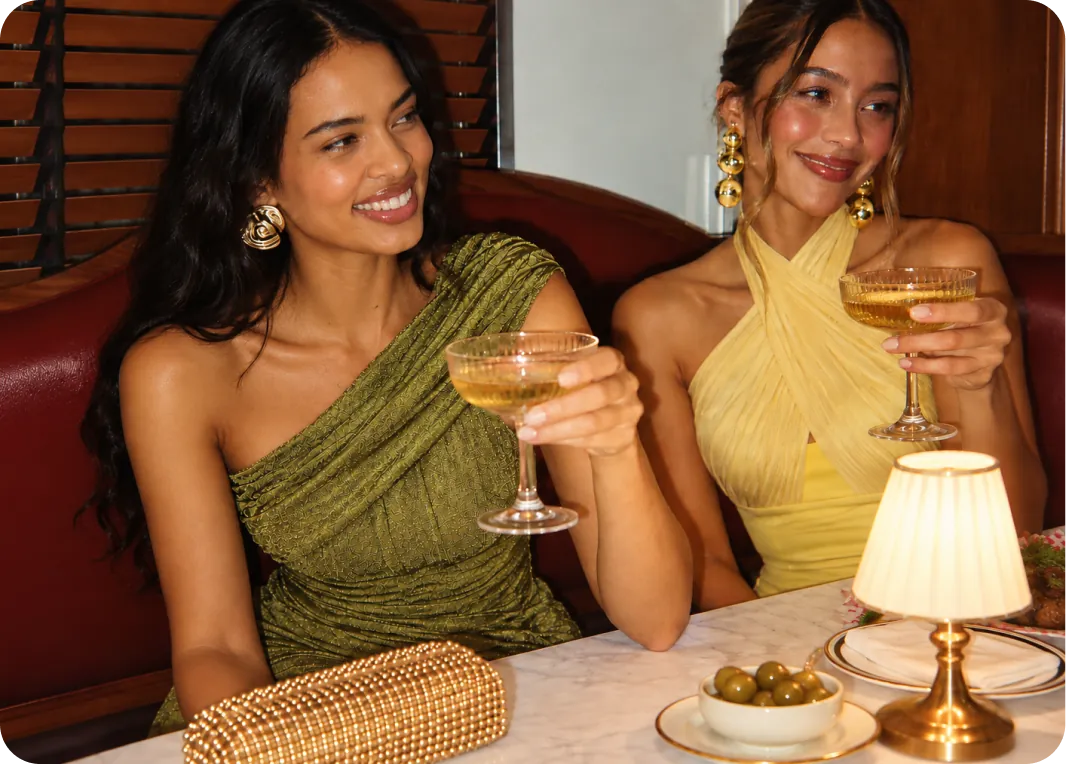 Dos invitadas brindando con vestidos alquilados en Click2Dress