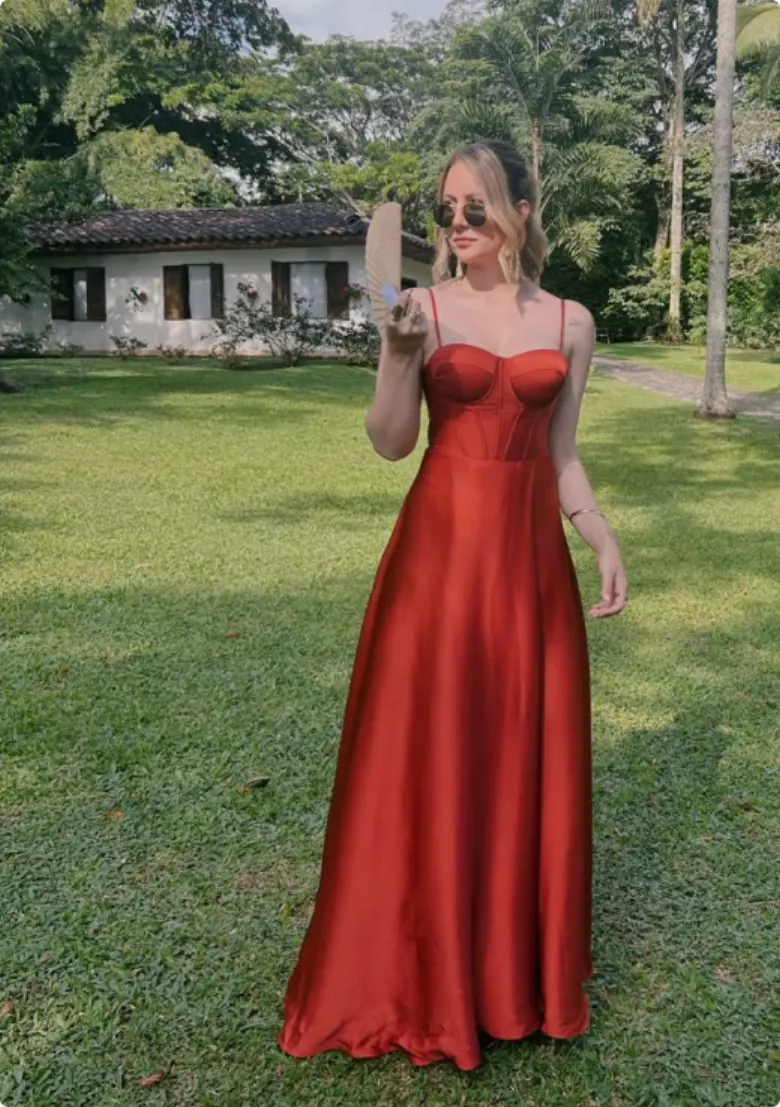 Invitada en vestido naranja quemado en un jardín