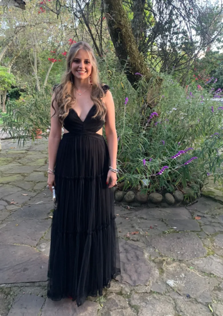 Invitada en vestido negro de tul con cutouts en un jardín